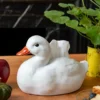 Boîte à mouchoirs en forme de canard blanc posée sur une table en bois, idéale pour une déco de cuisine ou de salon originale.