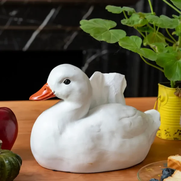 Boîte à mouchoirs en forme de canard blanc posée sur une table en bois, idéale pour une déco de cuisine ou de salon originale.
