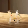 Verres à eau originaux servis avec une boisson lactée sur plateau bois et biscuits — ambiance gourmande et graphique.