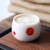 Gros plan d’un verre à eau coloré avec motif à pois rouges, idéal pour une décoration de table minimaliste et ludique.