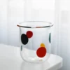 Détail du verre à eau coloré aux bulles rouges et bleues, parfait pour égayer un coin café.