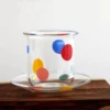 Coupelle en verre assortie au verre à eau coloré, décorée de pois vifs pour une présentation originale.