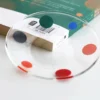 Verre à eau coloré au design festif, posé sur une table en bois pour un contraste chaleureux.