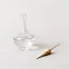 Collection de bouilloires en verre soufflé aux couleurs variées exposée sur une table minimaliste.