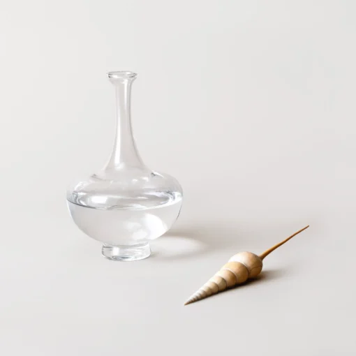 Collection de bouilloires en verre soufflé aux couleurs variées exposée sur une table minimaliste.