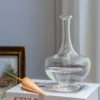 Bouilloire en verre turquoise avec bouchon coquillage dans un intérieur moderne et lumineux.