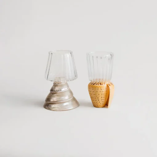 Deux verres à vins artisanaux avec base en coquillage, posés côte à côte sur fond beige neutre.