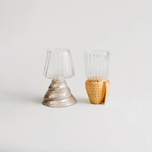 Deux verres à vins artisanaux avec base en coquillage, posés côte à côte sur fond beige neutre.