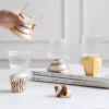 Scène décorative avec quatre verres à vins artisanaux et bases en coquillage naturel.
