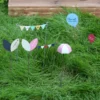 Accessoires décoratifs avec fanions et formes poétiques plantés dans l’herbe pour sublimer la décoration de pot de fleur.