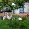 Scène bucolique composée de piques colorées et symboles vintage intégrée dans une décoration de pot de fleur au jardin.