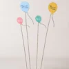 Vue rapprochée des motifs peints sur les piques métalliques, utilisés comme décoration de pot de fleur pour un jardin joyeux.