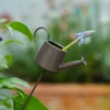 Arrosoir miniature noir avec fleur insérée, utilisé comme décoration pot de fleurs originale.