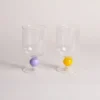 Ensemble de verres à vin posés à côté d’un citron décoratif et d’un support de cartes, ambiance méditerranéenne.