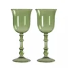 Gros plan sur un verre à vin original vert contenant des glaçons et une tranche d’agrume.