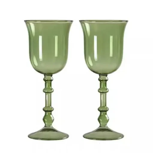 Gros plan sur un verre à vin original vert contenant des glaçons et une tranche d’agrume.