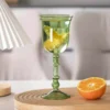 Verres à vin originaux verts avec tranches d’orange dans un décor lumineux et moderne.