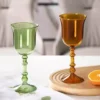 Verres à vin originaux en verre soufflé vert et ambre posés sur un plateau en bois