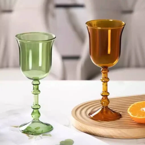 Verres à vin originaux en verre soufflé vert et ambre posés sur un plateau en bois