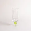 Verre à eau soufflé à la bouche avec détail de perle verte intégrée dans la tige, captant élégamment la lumière.