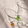 Mise en scène minimaliste avec deux verres à eau contemporains, jouant sur le contraste entre la transparence et la couleur.