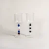 Deux verres à eau design contrastés par leur pied, présentés avec une bouteille de vin aromatisé.