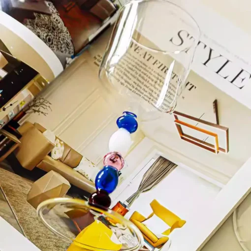 Verres à eau design posés sur un magazine de décoration, mettant en valeur les perles colorées du pied.