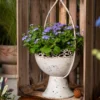 Pot de fleur blanc au charme ancien, associé à des fleurs violettes pour créer un contraste visuel doux et raffiné.