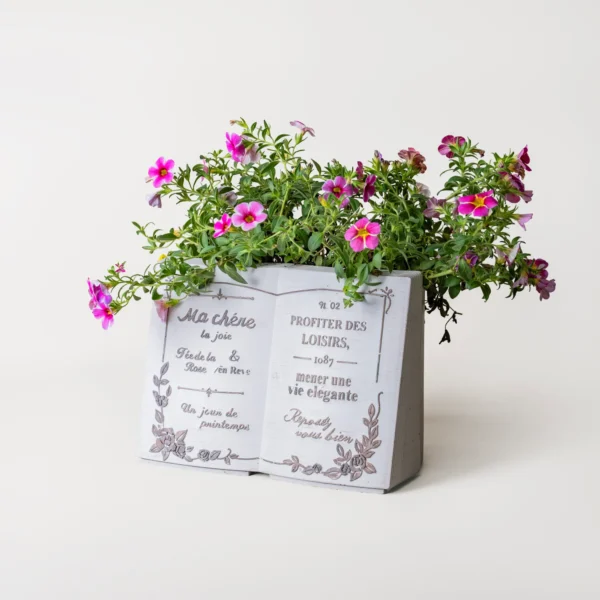 Pot de fleur en forme de livre blanc avec fleurs violettes, parfait pour la décoration intérieure ou extérieure.