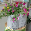 Pot de fleur livre avec reliefs et fleurs roses, mis en scène sur un tabouret vert vintage.