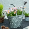 Gros plan sur les reliefs floraux en métal vieilli d’un pot de fleur en suspension original.