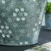 Pot de fleur en suspension utilisé avec des marguerites roses sur une table de jardin.