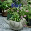 Grand pot de fleur intérieur en magnésie, décoré avec des fleurs violettes dans un environnement de jardin naturel.