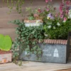 Pot de fleurs intérieur avec plantes tombantes et toit effet tôle ondulée, style champêtre.