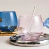 Verres à eau pastel rose et bleu avec pailles en verre assorties sur plateau chromé