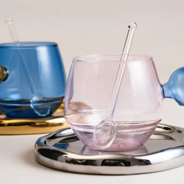 Verres à eau pastel rose et bleu avec pailles en verre assorties sur plateau chromé
