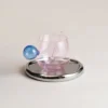 Verres à eau originaux posés sur un plateau rond chromé, modèle rose à cuillère intégrée