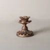 Petit bougeoir doré à base ronde, orné de motifs floraux pour un style vintage.