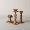 Trio de bougeoirs dorés en métal vieilli, parfaits pour une décoration de table élégante.