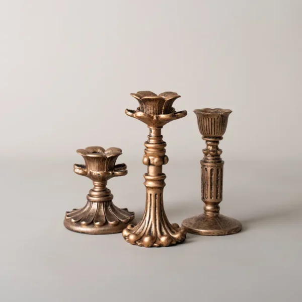Trio de bougeoirs dorés en métal vieilli, parfaits pour une décoration de table élégante.