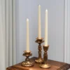 Bougeoir doré avec bougie effilée blanche, placé sur une console pour une ambiance romantique.