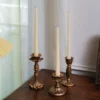 Ensemble de trois bougeoirs dorés assortis, chacun avec une forme différente et originale.