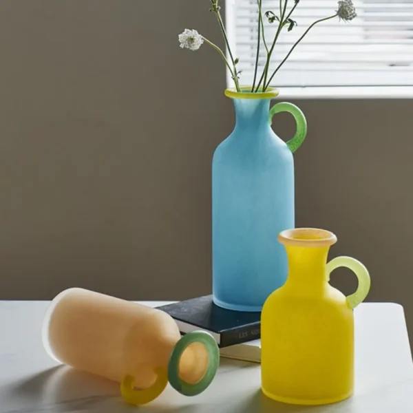 Ensemble artistique de vases en verre soufflé aux poignées colorées, parfaits pour jouer sur les contrastes dans une déco moderne.
