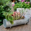 Jardinière tubulaire posée sur table en bois, parfaite comme pot de fleurs moderne pour balcon ou intérieur.