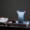Vase pour tulipes placé sur des livres d'art, entouré d'une ambiance calme et raffinée.