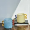 petit vase beige à anses jaunes et bleues