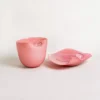 Vase déco design en verre rose opaque avec ouverture évasée, présenté sur un fond beige neutre.