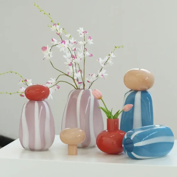 Composition florale dans un vase rayé rose avec fleurs blanches et roses, pour une ambiance douce.